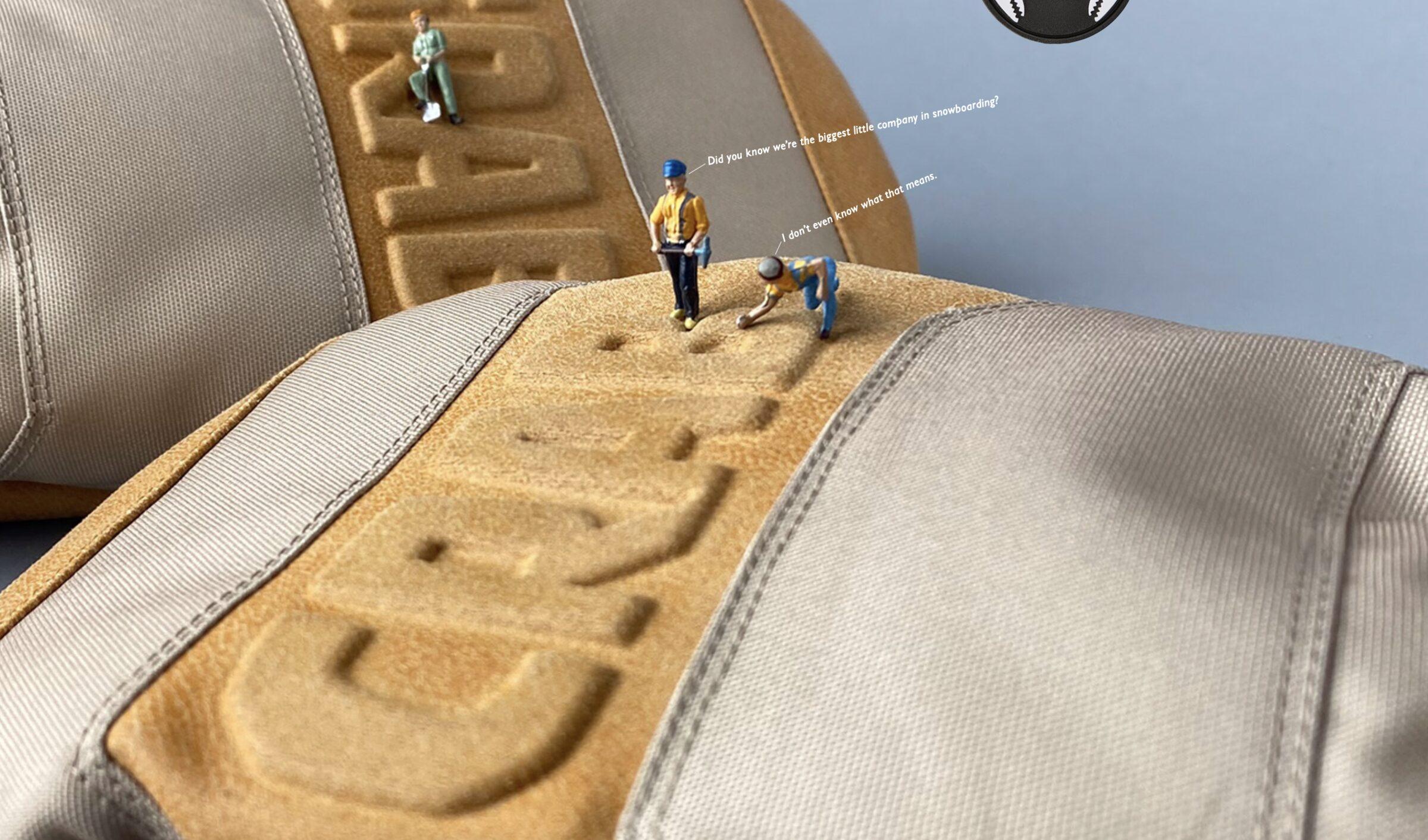 Gros plan sur une casquette beige et grise avec le mot CRANK en relief sur le devant