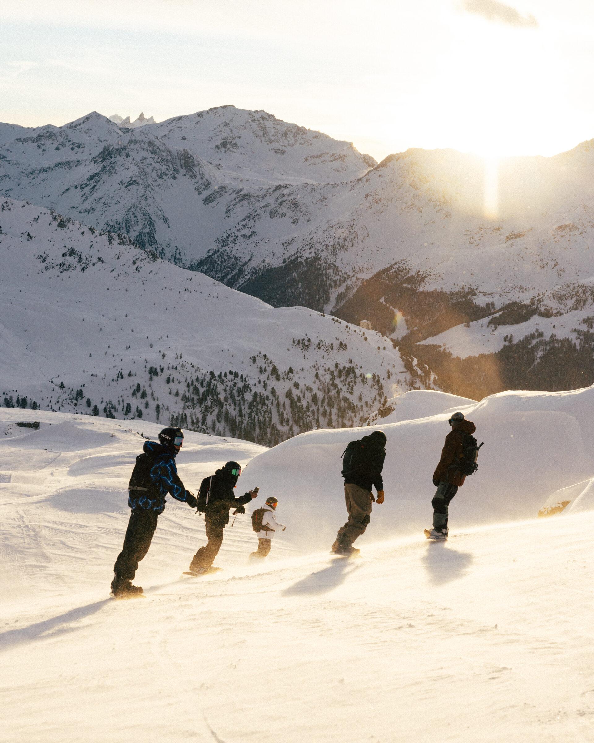 Groupe de riders descendant une pente enneigée au coucher du soleil, photographie noir et blanc